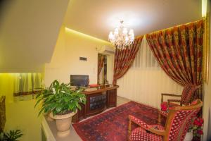 sala de estar con lámpara de araña, sofá y TV en Vila Tako - Hotel, en Tirana