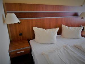 uma cama com duas almofadas brancas e uma cabeceira em madeira em Haus Vier Jahreszeiten am See HS 581 em Goslar