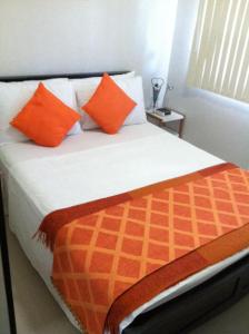 1 cama con almohadas de color naranja y blanco en una habitación en Sea Residences Holiday Rentals, en Manila