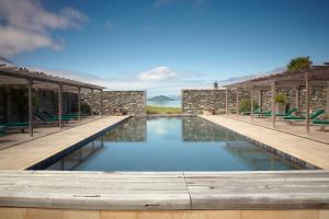 a swimming pool with wooden benches and chairs at Blanket Bay in Glenorchy