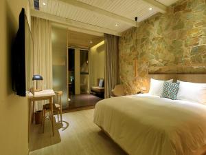 a bedroom with a large bed and a stone wall at EBO Hotel Zijin gang Asian Games Park Store Zhejiang university in Hangzhou