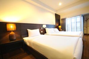a hotel room with two beds and a window at Kasemsarn Hotel Chanthaburi in Chanthaburi