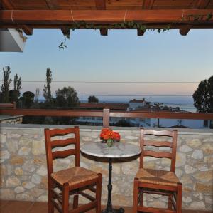 two chairs and a table with flowers on a patio at Villa Maraki in Agia Paraskevi