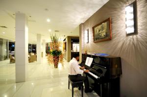 Ein Mann, der auf einem Klavier in einer Lobby sitzt. in der Unterkunft Kasemsarn Hotel Chanthaburi in Chanthaburi