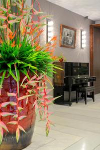 a large vase with plants in a room with a piano at Kasemsarn Hotel Chanthaburi in Chanthaburi