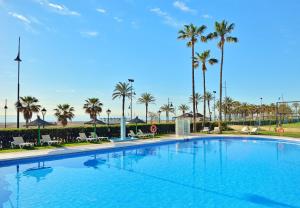 een groot zwembad met palmbomen en een strand bij Sol Principe in Torremolinos