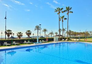 a large swimming pool with palm trees and a beach at Sol Principe in Torremolinos