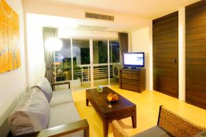 a living room with a couch and a table and a television at Kasemsarn Hotel Chanthaburi in Chanthaburi