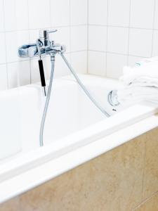 a bath tub with a shower head and towels at Hotel Kockska Gården in Simrishamn