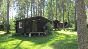 una persona parada frente a una cabaña en un bosque en Camping Lappeenranta, en Lappeenranta
