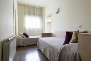 a hotel room with two beds and a window at Residencia Universitaria Los Abedules in Pamplona