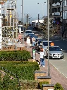 a group of people walking down a street with cars at Appart Noah in Knokke-Heist