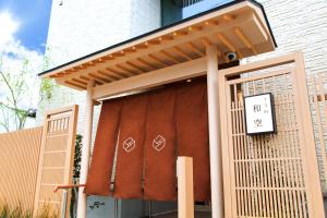 d'une porte menant à un bâtiment avec un panneau. dans l'établissement Waqoo Shitaderamachi, à Osaka
