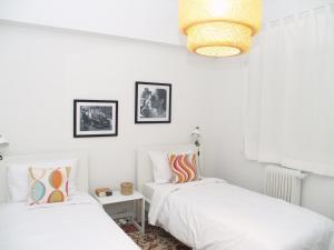 Habitación con 2 camas, paredes blancas y lámpara de araña. en Artistic Deco Apartment, en Atenas