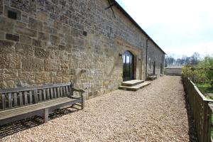 a stone wall with a bench next to a building at Withyslade Farm in Tisbury