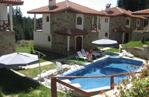 una casa con piscina con sedie e ombrelloni di Snow White's Secret Chalet in the Forest a Pamporovo
