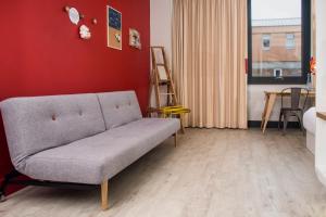 a living room with a couch and a red wall at The Corner London City in London