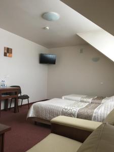 1 dormitorio con 2 camas y TV en la pared en Hotel Magnolia, en Kielce