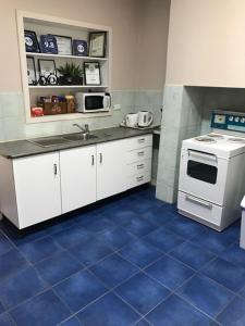 a kitchen with a white stove and a blue tile floor at Jadan Cottages in Broken Hill