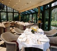 a restaurant with white tables and chairs and windows at Romantik Hotel Jagdhaus Waldfrieden in Bilsen