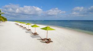 a row of beach umbrellas sitting on top of a sandy beach at South Palms Resort Panglao in Panglao