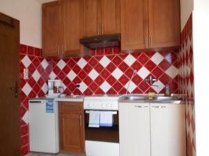 a kitchen with a red and white tiled wall at Apartments u Kapetana in Punat
