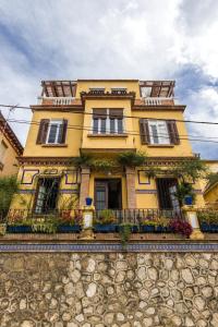 a yellow house with windows and balconies on a stone wall at Villa Alicia Guest House in Málaga