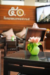 a flower in a green vase sitting on a table at Kasemsarn Hotel Chanthaburi in Chanthaburi