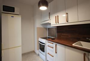 a kitchen with white cabinets and a white stove top oven at Kawalerka cynamonowa in Gdańsk