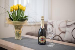 a bottle of champagne next to a vase of yellow flowers at Fajne Apartamenty - Karwia - Blisko Plaży - Komfort i Cisza in Karwia