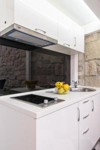 a white kitchen with a sink and a stove at Studio Apartman REA in Trogir