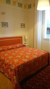 ボローニャにあるCasa Isolani Piazza Maggiore 1.0のベッドルーム1室(オレンジ色の掛け布団、窓付)