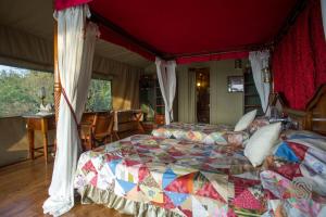 a bedroom with a large bed with a canopy at Kirawira Serena Camp in Handajega