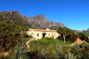 una casa en una colina con una montaña en el fondo en The Cottage @ Montpellier en Franschhoek