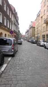 a cobblestone street with parked cars in a city at Nasz Klub - Pokoje Gościnne in Poznań