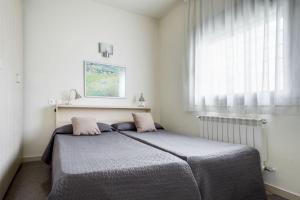 Schlafzimmer mit einem Bett mit rosa Kissen und einem Fenster in der Unterkunft Residencia Universitaria Los Abedules in Pamplona