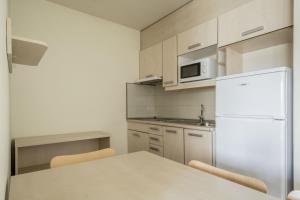 cocina con mesa y nevera blanca en Residencia Universitaria Los Abedules en Pamplona