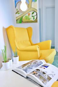 アーチ・トレッツァにあるVilla Albaの黄色い椅子とテーブルに座る本