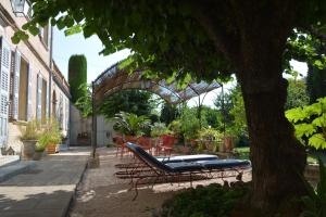 a patio with a bench and tables and a tree at Les Passiflores in Grasse