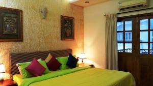 a bedroom with a green bed with colorful pillows at CANDOLIM BEACH VILLA # 3BHK # POOL # KITCHEN # 300Mts to Beach by GR stays in Candolim +42 photos