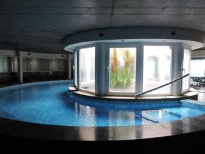 een groot zwembad in een gebouw met een groot raam bij Linda Bay Spa Apartments in Mar de las Pampas
