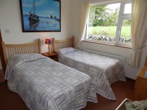 two beds in a room with two windows at Meadowfield in Ballyvaughan +21 photos