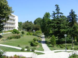 a park with a building and trees and bushes at Neptune Hotel in Saints Constantine and Helena