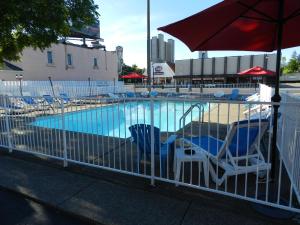 een zwembad met stoelen en een parasol bij Kings Inn Near the Falls in Niagara Falls