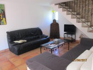 a living room with a black leather couch and a table at Au carrefour Vallée de la Cèze in Bagnols-sur-Cèze