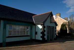 uma casa branca e preta com uma entrada de tijolos em Old School House Belcoo 41 em Belcoo