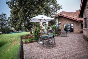 a table and chairs with an umbrella on a brick patio at First Group Qwantani in Harrismith