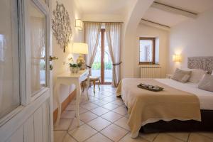 a hotel room with a bed and a desk and a window at Tenuta Del Poggio Antico in Ischia