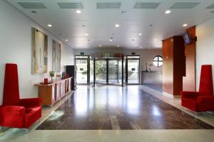 a lobby with red chairs and a reception desk at Exe Gran Hotel Almenar in Las Rozas de Madrid