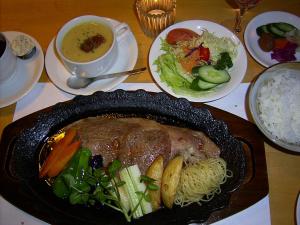 einen Tisch mit einer Mahlzeit aus Fleisch, Gemüse und Reis in der Unterkunft Ashita no Mori in Hongu